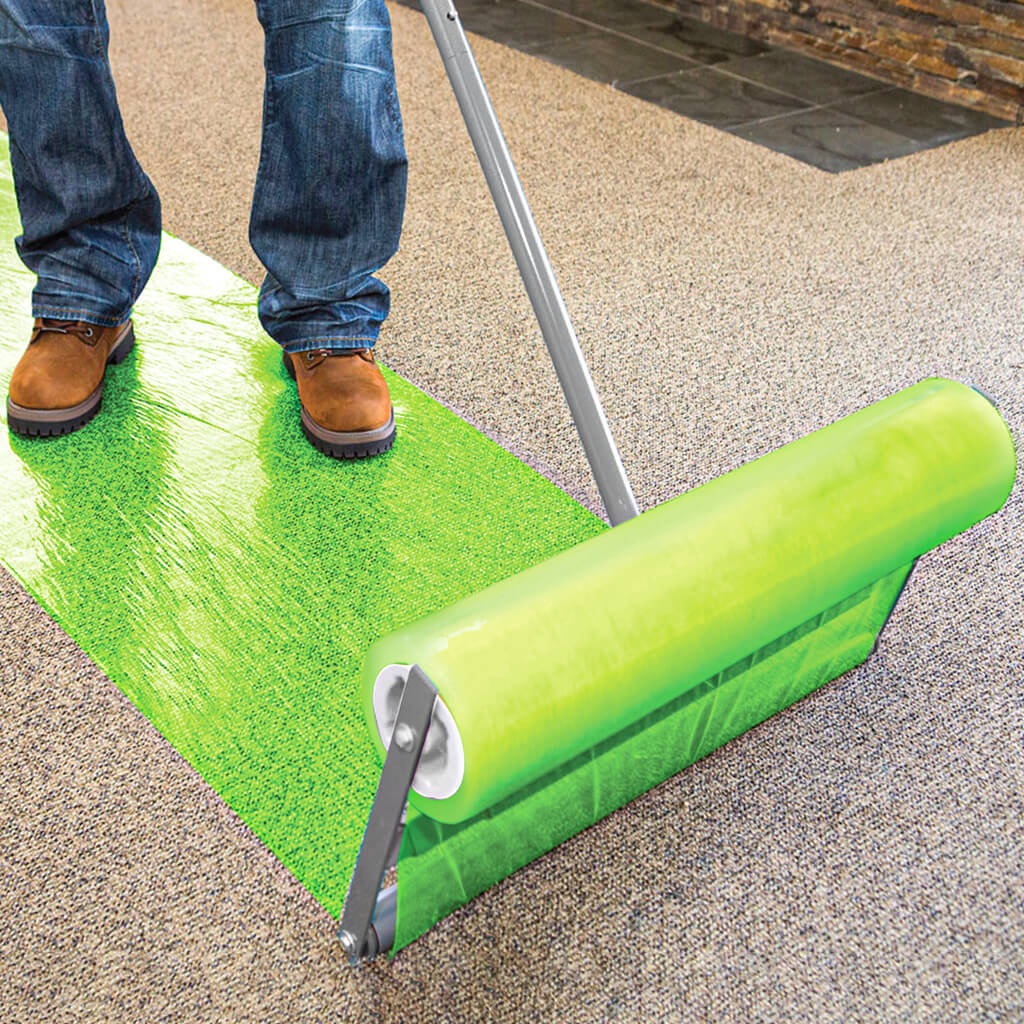 person using an applicator to apply protective flooring film to carpet
