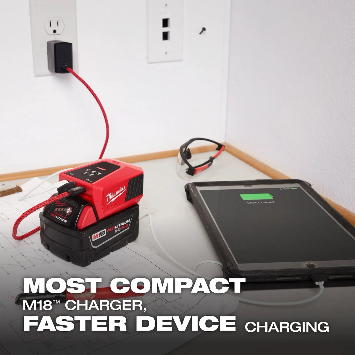 Milwaukee M18 TOP-OFF charger powering a device on a workbench