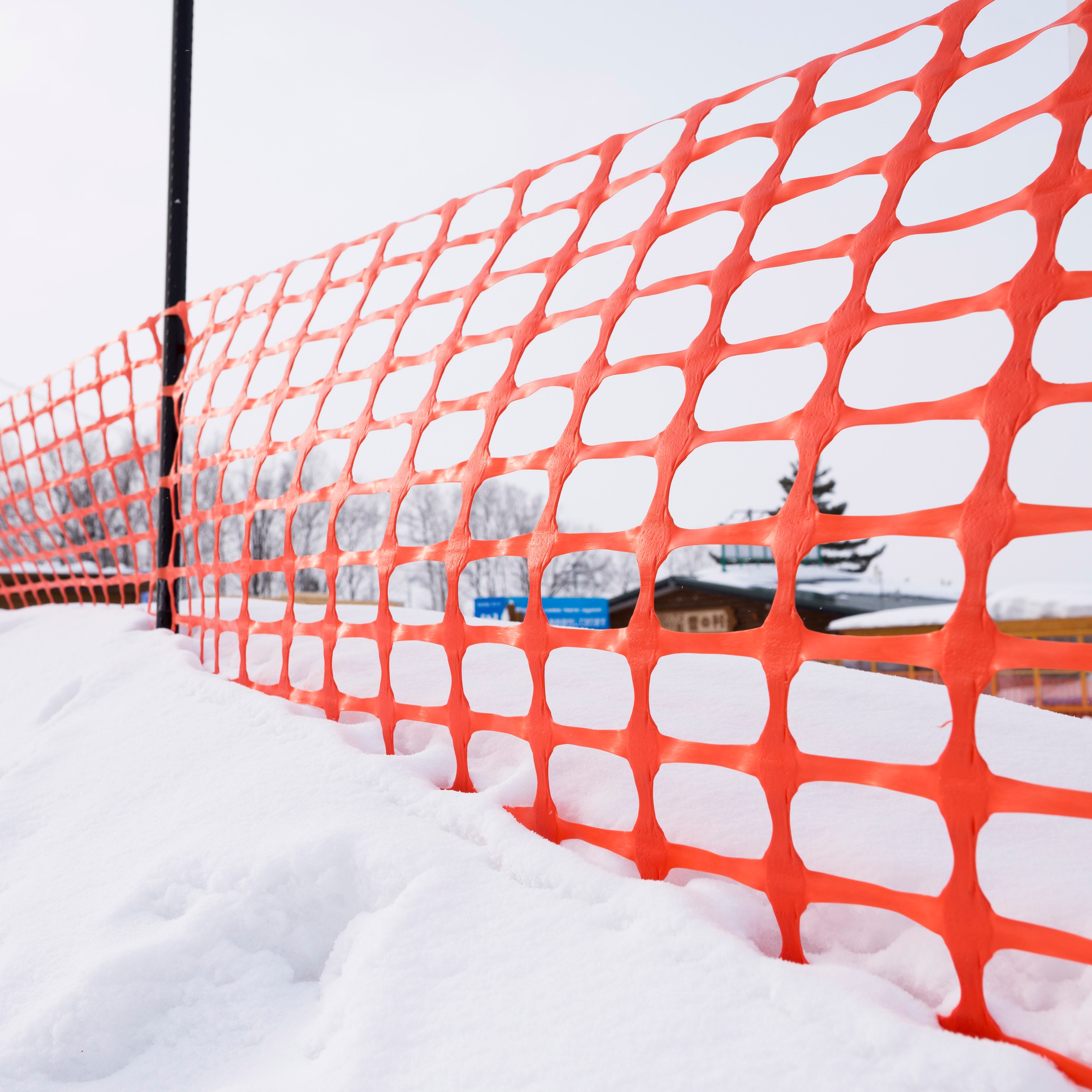 Orange safety fence with snow accumulation in a winter setting